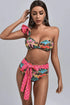 Colorful high-waisted bikini with pink polka dot ruffles and bow detail on model
