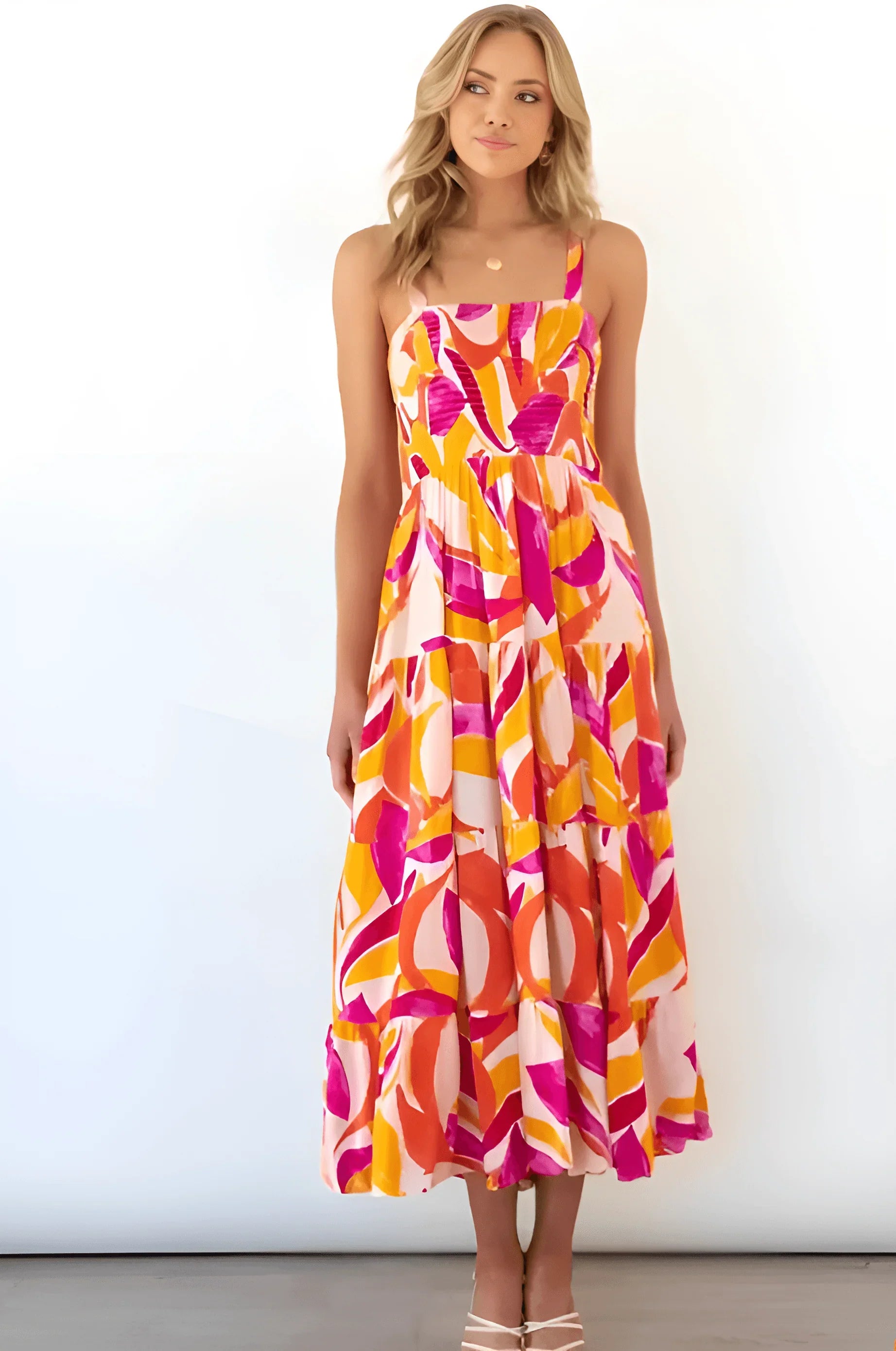 Woman wearing a colorful sleeveless Charlotte Day Dress with vibrant pink, orange, and yellow patterns, perfect for summer and beach outings.