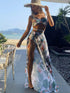 Woman wearing floral drawstring strap swimsuit set with matching mesh skirt and wide-brimmed hat at beachside patio
